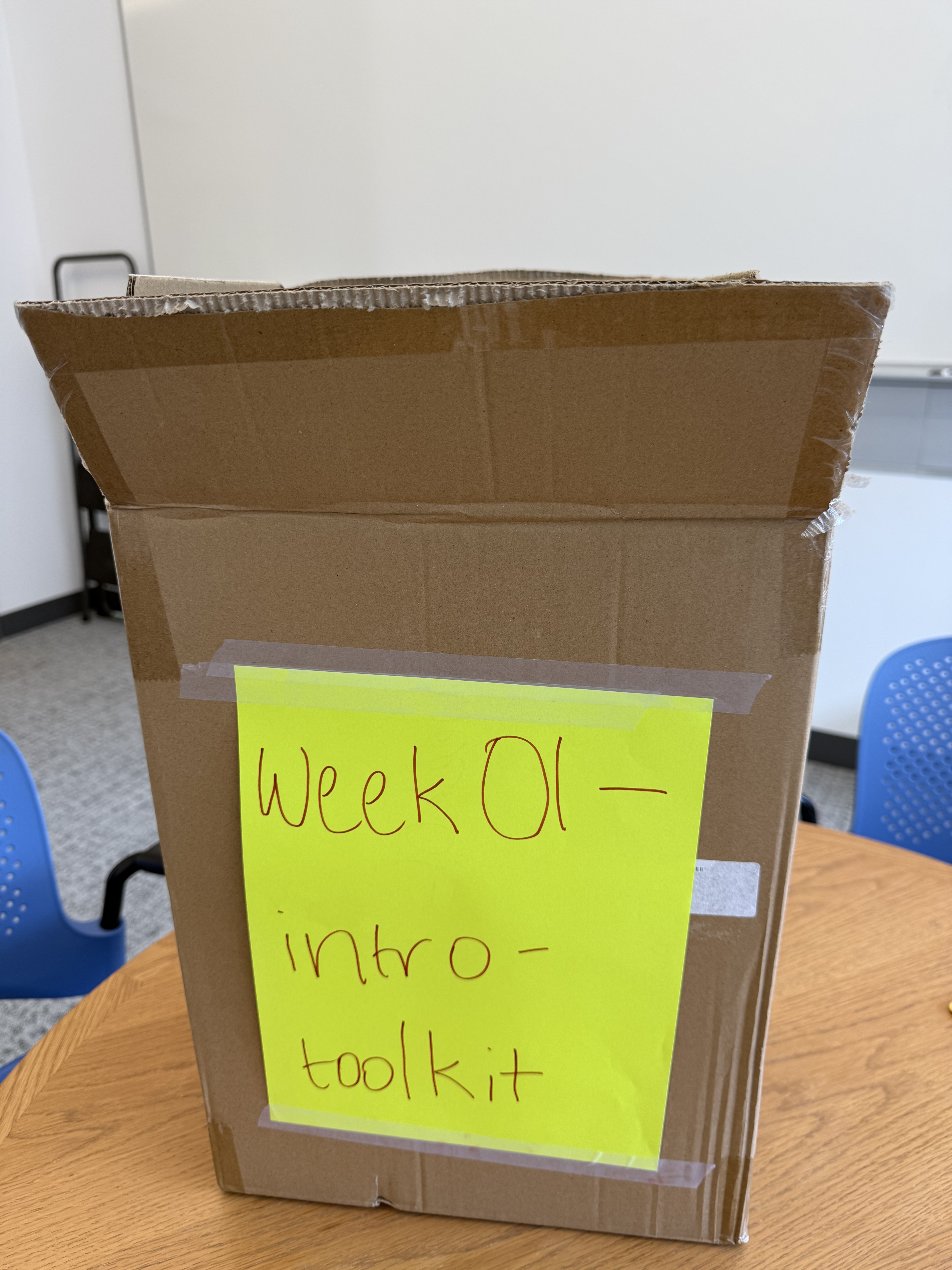 A cardboard box on a table with a yellow sign that reads week01-intro-toolkit.